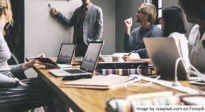 Sekelompok orang di ruang rapat mengadakan pertemuan untuk membahas manajemen perubahan untuk inisiatif digital skala besar.