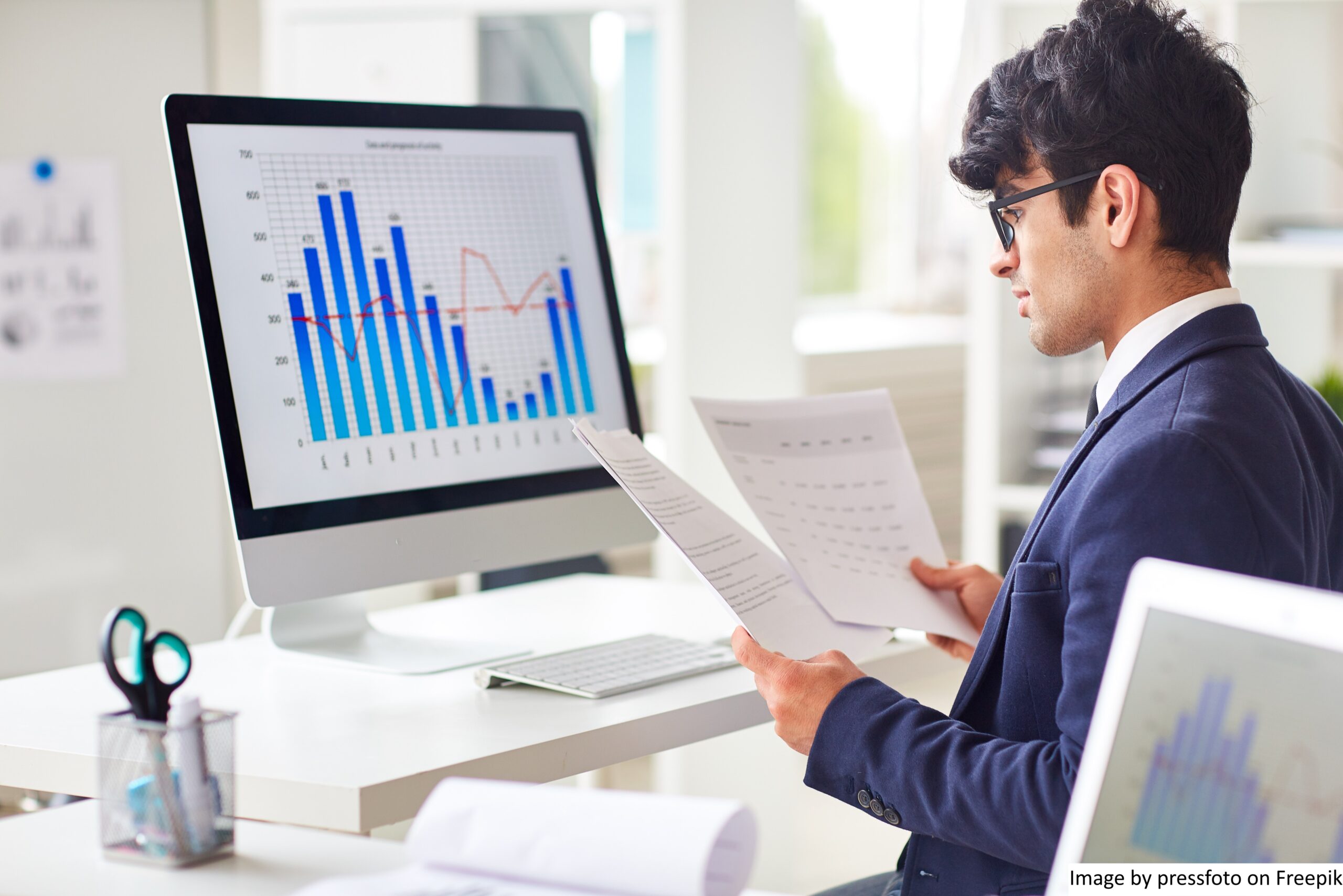 A man sitting in front of a monitor screen showing customer journey analytics in retail across every touchpoint. He is trying to find ways to optimize the business