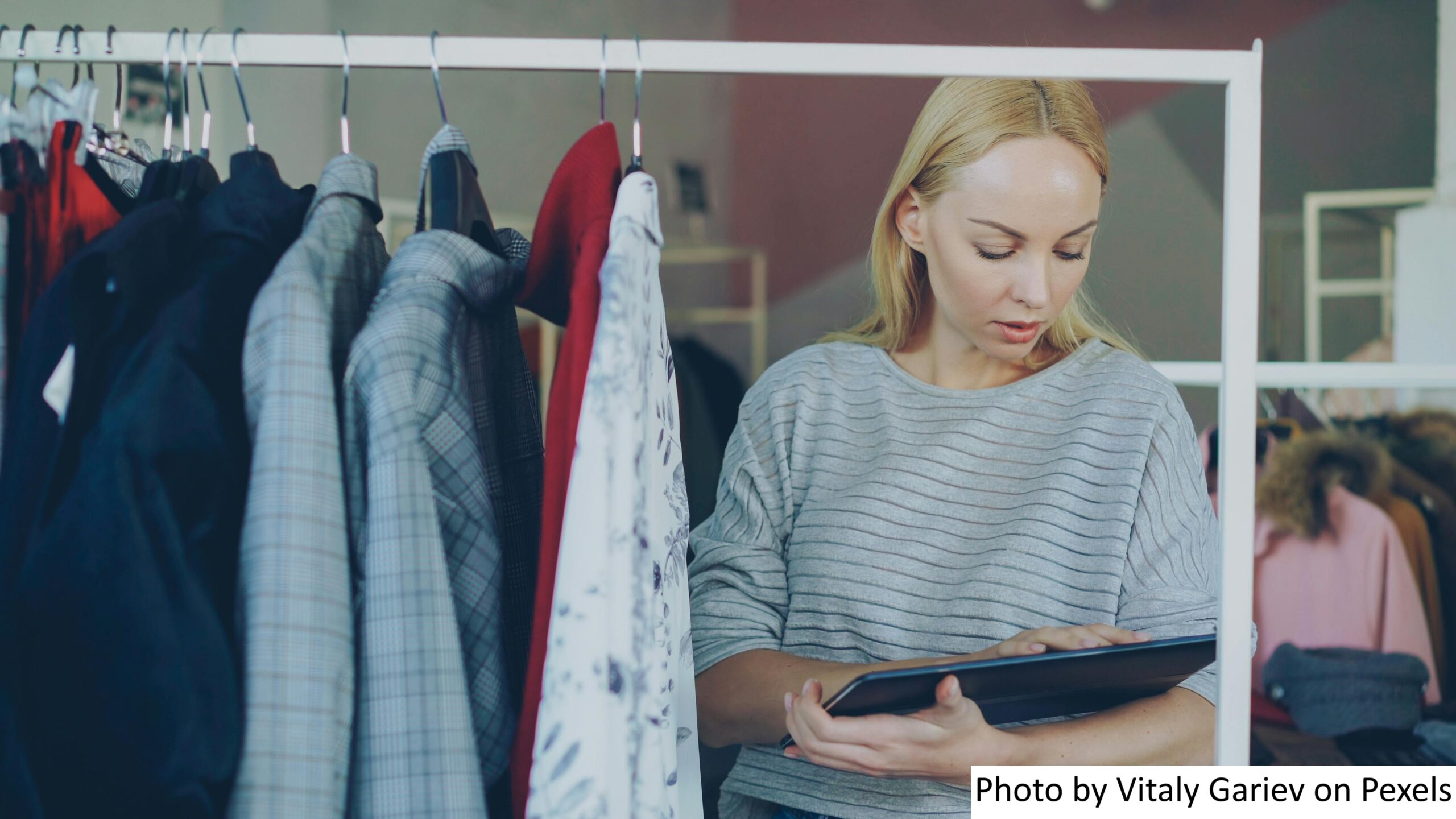 A woman in a fashion retail store that has adopted retail automation using a tablet to check the store’s inventory. 