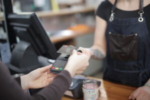 A staff member serving a customer at a retail checkout counter with a point-of-sale terminal