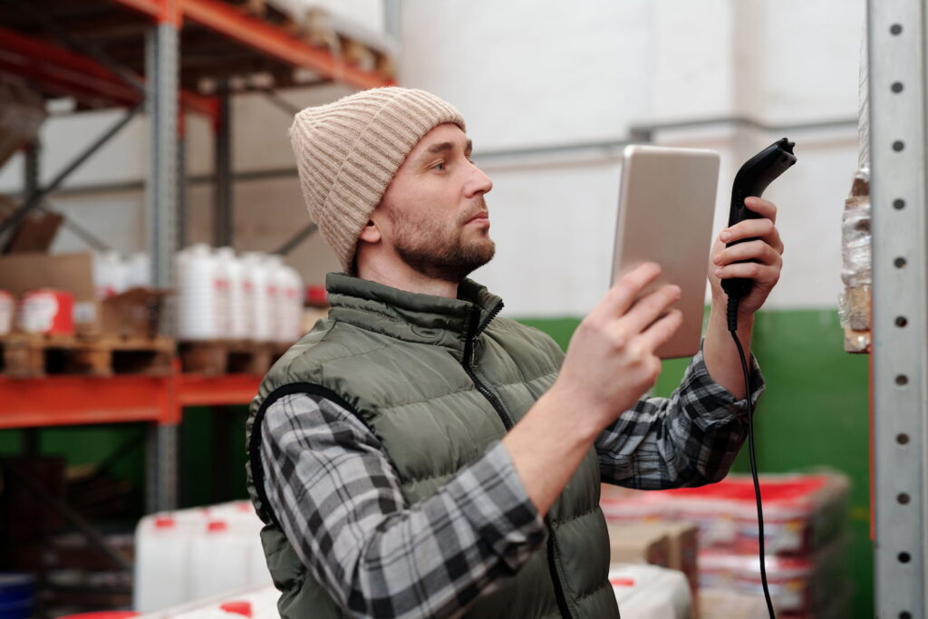 A retail associate checking stock on a handheld device among clothing rails